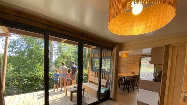 A modern interior with large glass doors, a wooden deck, and a kitchen area.