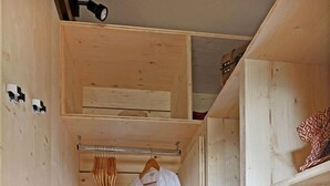 Una stanza in legno angusta con un appendiabiti a parete, uno scaffale con un panno rosso e un piccolo cesto.