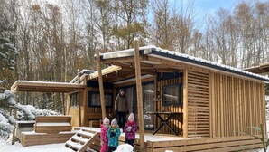 Una baita di legno con un portico, una panchina e una scala che conduce all'ingresso.