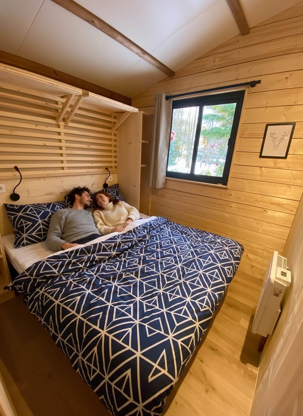 Une chambre confortable, aménagée dans le style d’un chalet, avec un lit, des murs en bois et une fenêtre donnant sur un paysage verdoyant.