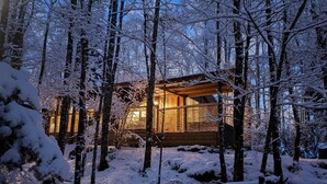 A wooden cabin surrounded by snow-covered trees.