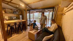 Ein gemütliches Interieur mit einer Essgegend aus Holz, einer Küche mit modernen Geräten und einem großen Fenster mit Blick ins Freie.