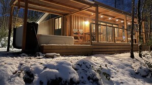 Eine Holzjagdhaus mit überdachter Veranda, einer Couch und einem Esstisch.