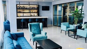 A modern lounge area with a bar, seating arrangements, and a large window. - Standard Queen Room at Tris Estates Hotel & Suites (Duazon)
