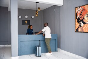 Welcome to our reception area, featuring a modern reception desk with a digital clock displaying international time zones and a beautiful artwork above.