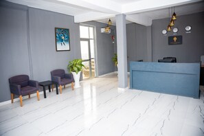 Welcome to our reception area, featuring a sleek reception desk, comfortable seating, and a beautiful potted plant.