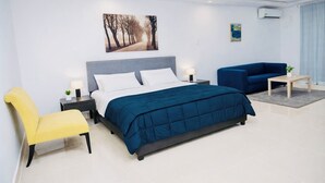 Une chambre d’hôtel moderne avec un grand lit, un canapé, un fauteuil et une petite table.