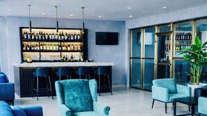 Un espace de détente moderne comprenant un bar, des coins salon et une grande fenêtre.
