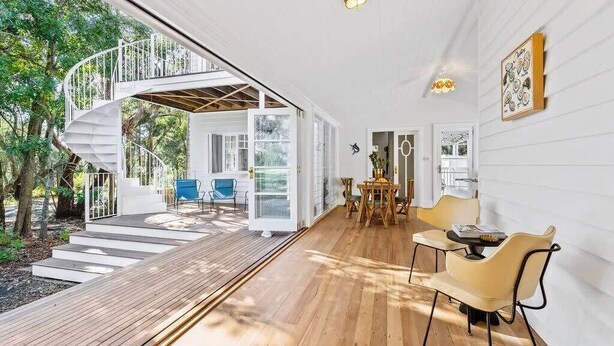 A modern interior with a spiral staircase leading to a deck, a dining area with chairs, and a view of the outdoors.