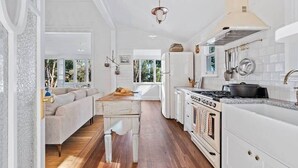 A modern kitchen with white cabinetry, a wooden dining table, and a built-in oven.