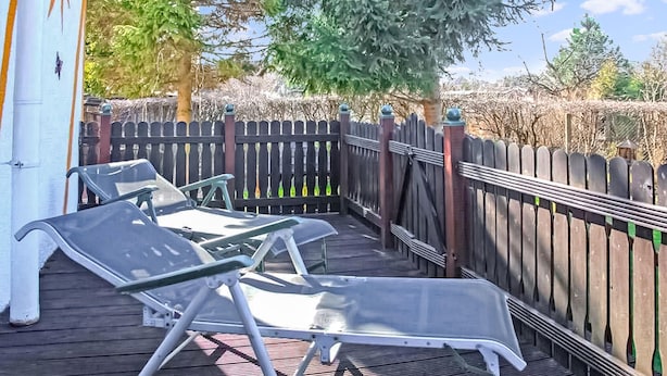 A covered outdoor deck with two lounge chairs and a wooden fence. - Ferienhaus Waren (Müritz) (Waren (Müritz))