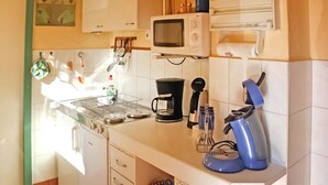 A kitchen with a microwave, coffee maker, and utensils on the counter. - Ferienhaus Waren (Müritz) (Waren (Müritz))