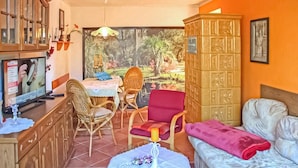 A cozy living room with a television, wicker chairs, a red armchair, a sofa, and a decorative cabinet. - Ferienhaus Waren (Müritz) (Waren (Müritz))