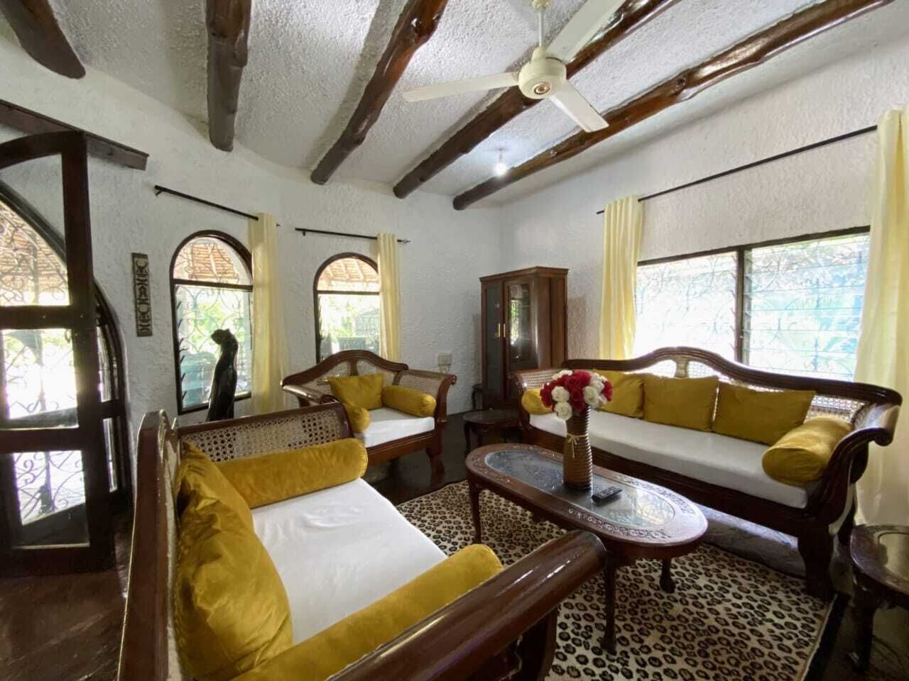 Um quarto com uma cama, dois sofás, uma mesa e um ventilador de teto.