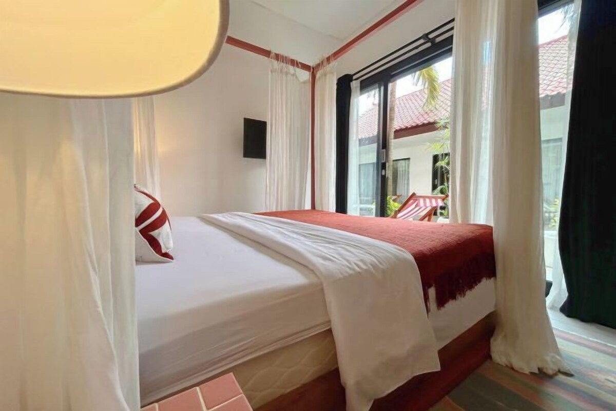 A hotel room with a bed, a TV, and a view of the outside.