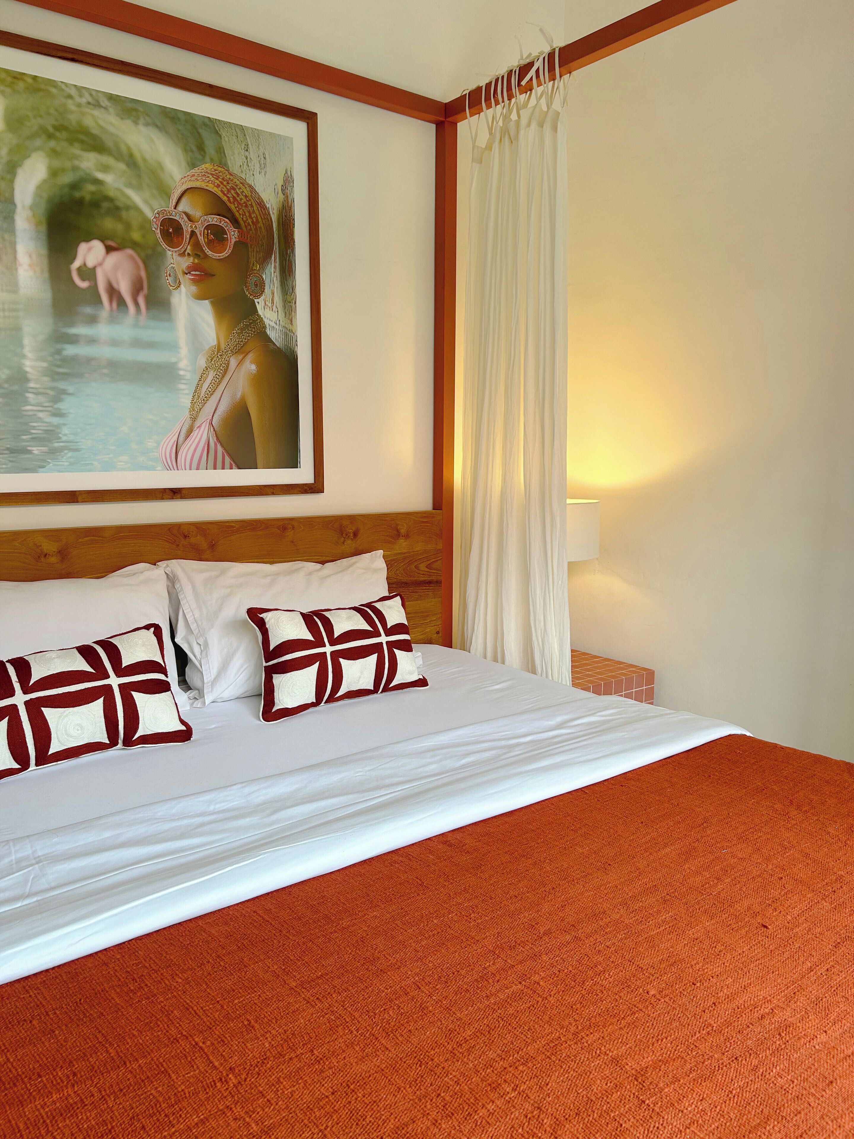 A hotel room with a large bed, white bedding, and a painting of a woman in a pool.