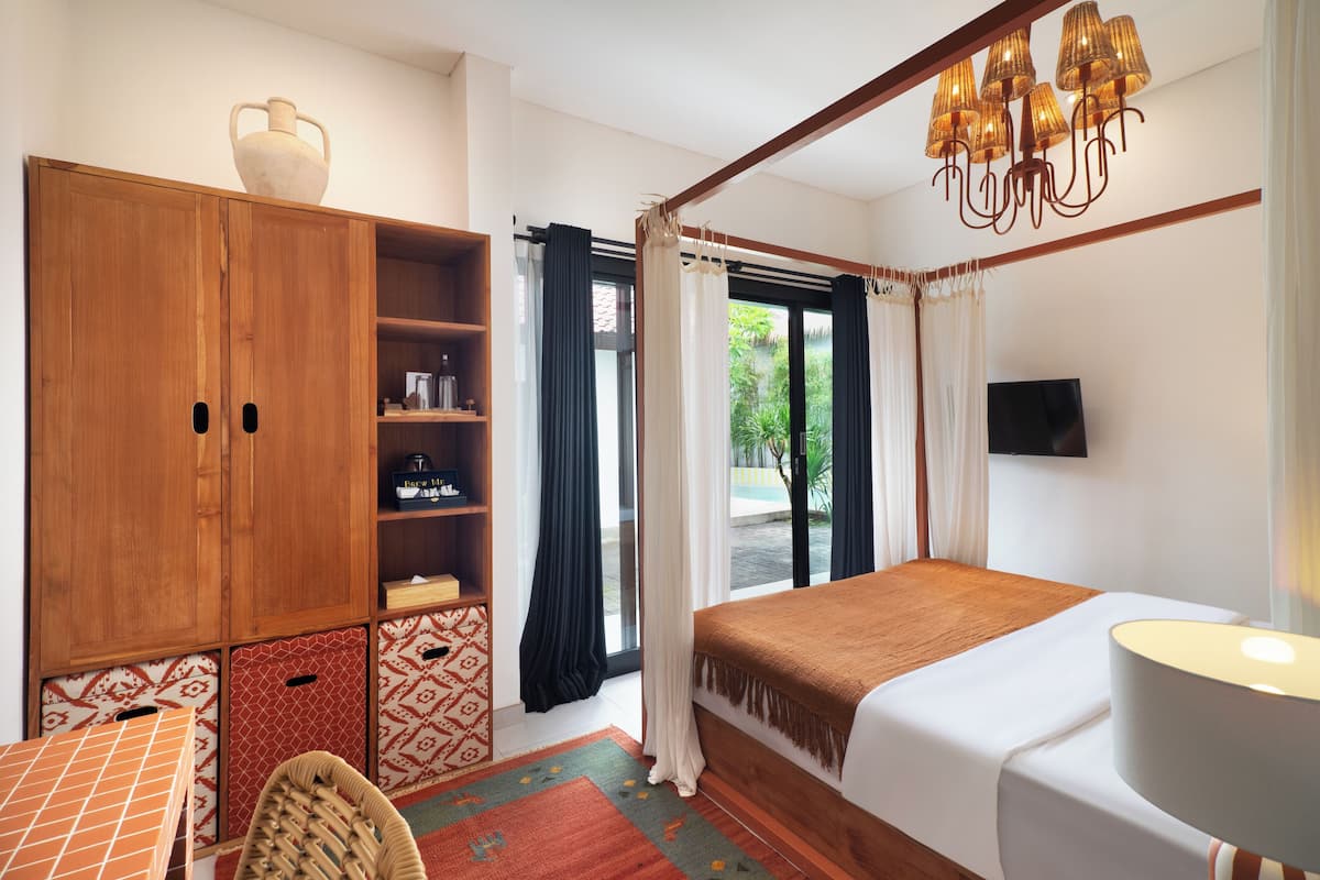 Un dormitorio con cama, armario de madera, televisor y ventana con cortinas.
