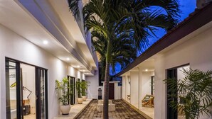 A modern building with a central courtyard featuring a palm tree, potted plants, and a tiled floor. - Berawa Nest Canggu (Tibubeneng)