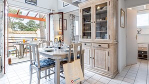 Un coin repas avec une table dressée pour quatre personnes, un meuble avec des portes en verre et une vue sur l’extérieur grâce à une porte vitrée.