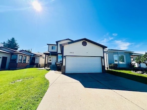 A residential area with houses, a clear sky, and a well-maintained lawn.