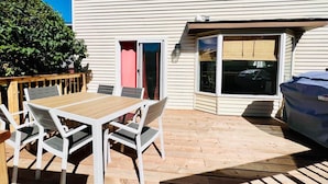 A patio with a wooden table and chairs, a covered grill, and a sliding glass door leading to a garage. - FunKidHouse*NearWEM*FamilyBabyKidFriendly*Kingbed* (Edmonton)
