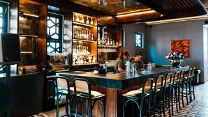 Eine Bar mit einer langen Theke, Hockern und einem Barista, der Getränke zubereitet.