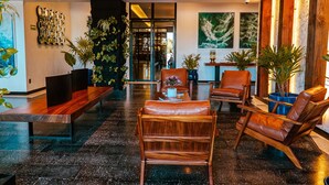 Eine moderne Lobby mit Holzmöbeln, großen Kübelpflanzen und Kunstwerken an den Wänden.