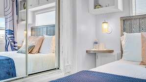 Une chambre d’hôtel avec un grand lit, un lit plus petit, une table de chevet, un miroir, une fenêtre avec vue et un luminaire fixé au mur.