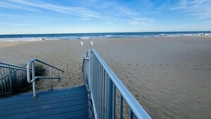 Une plage avec une rambarde en métal et un escalier menant à la plage.