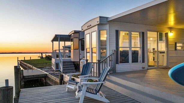 Une propriété située au bord de l’eau, dotée d’une terrasse, d’un espace salon extérieur et d’une piscine.