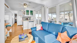 Un salon moderne avec un canapé bleu, une table basse ronde et un ventilateur de plafond.