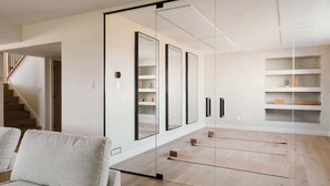 Ein modernes Interieur mit einer Treppe, einer Couch sowie einer Wand mit Spiegeln und Regalen.