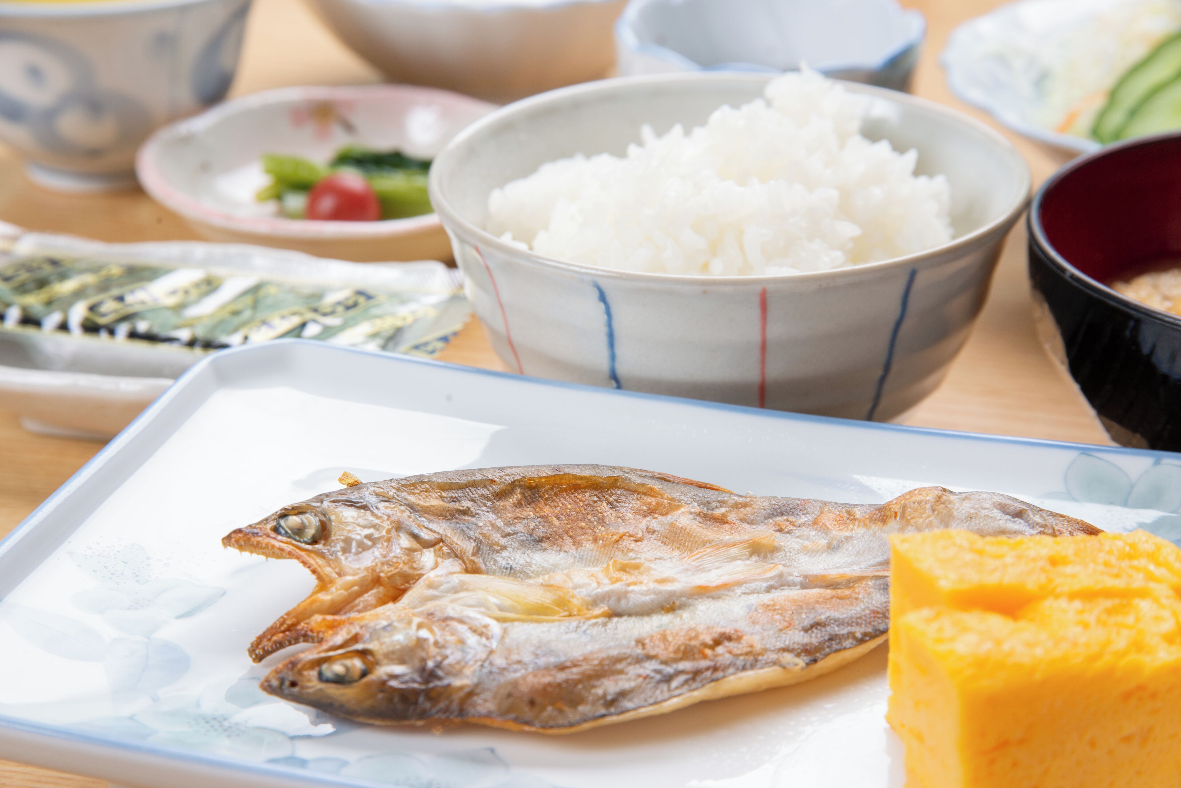Una mesa de comedor con una variedad de platos, incluyendo arroz, pescado y un postre amarillo.