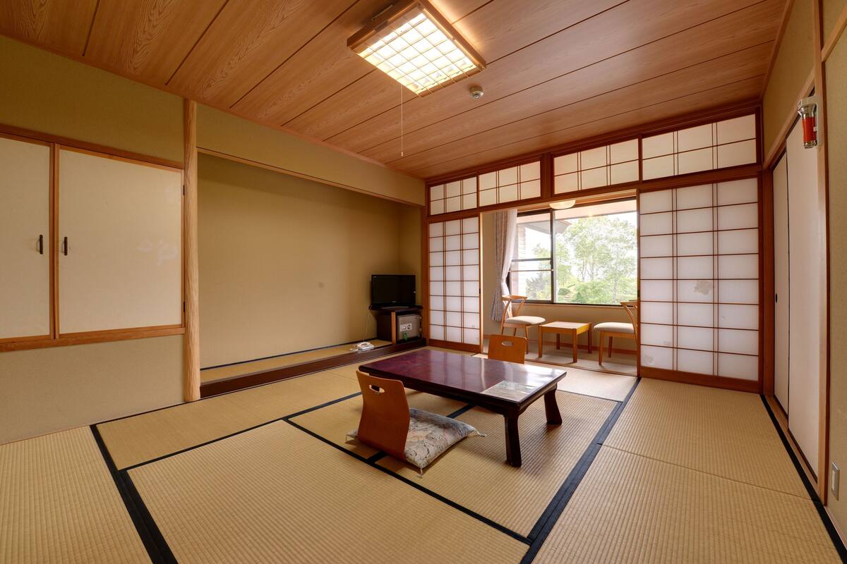 A traditional Japanese room with tatami flooring, a low table, and sliding doors.