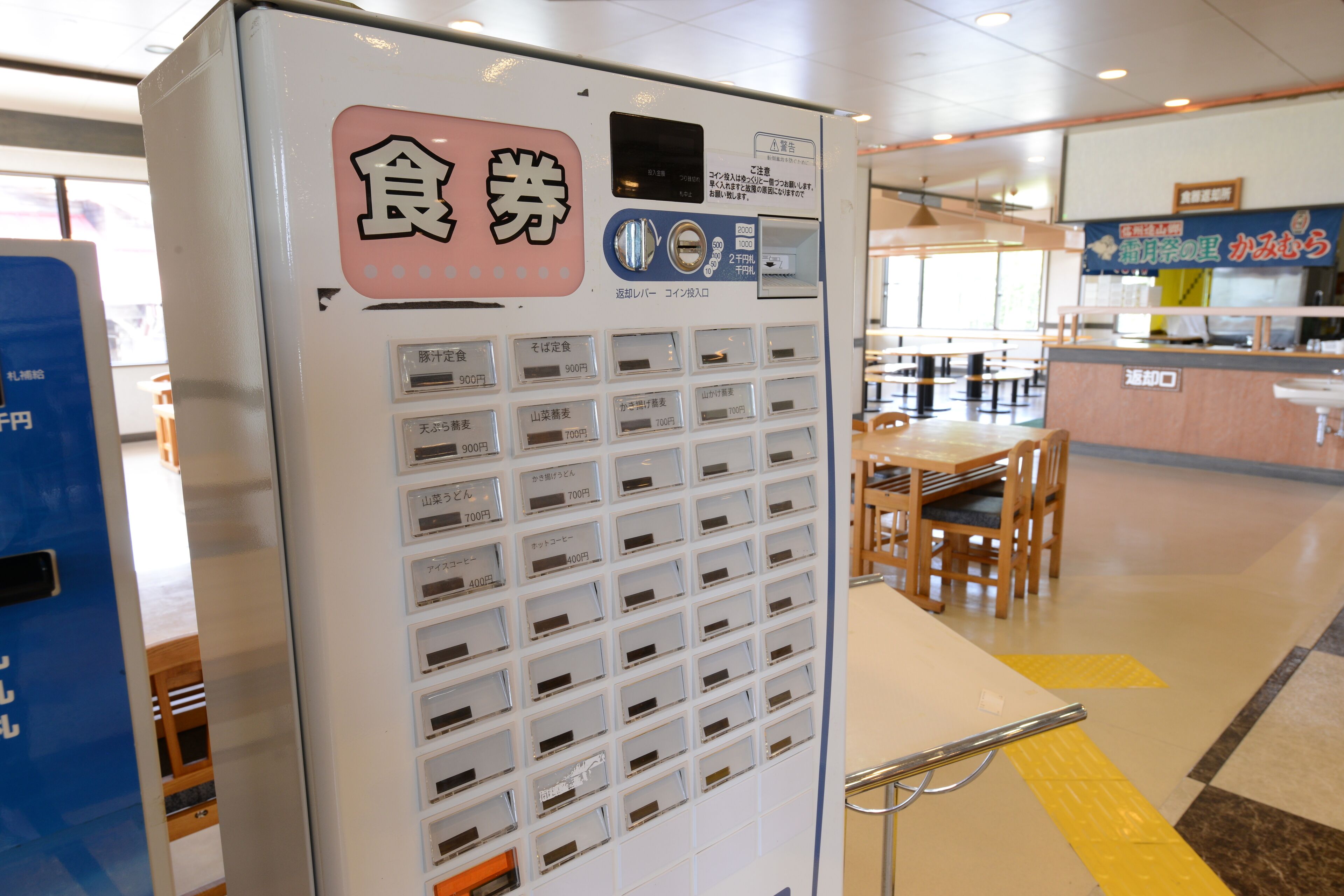 A vending machine with multiple compartments, each labeled with different prices in Japanese.