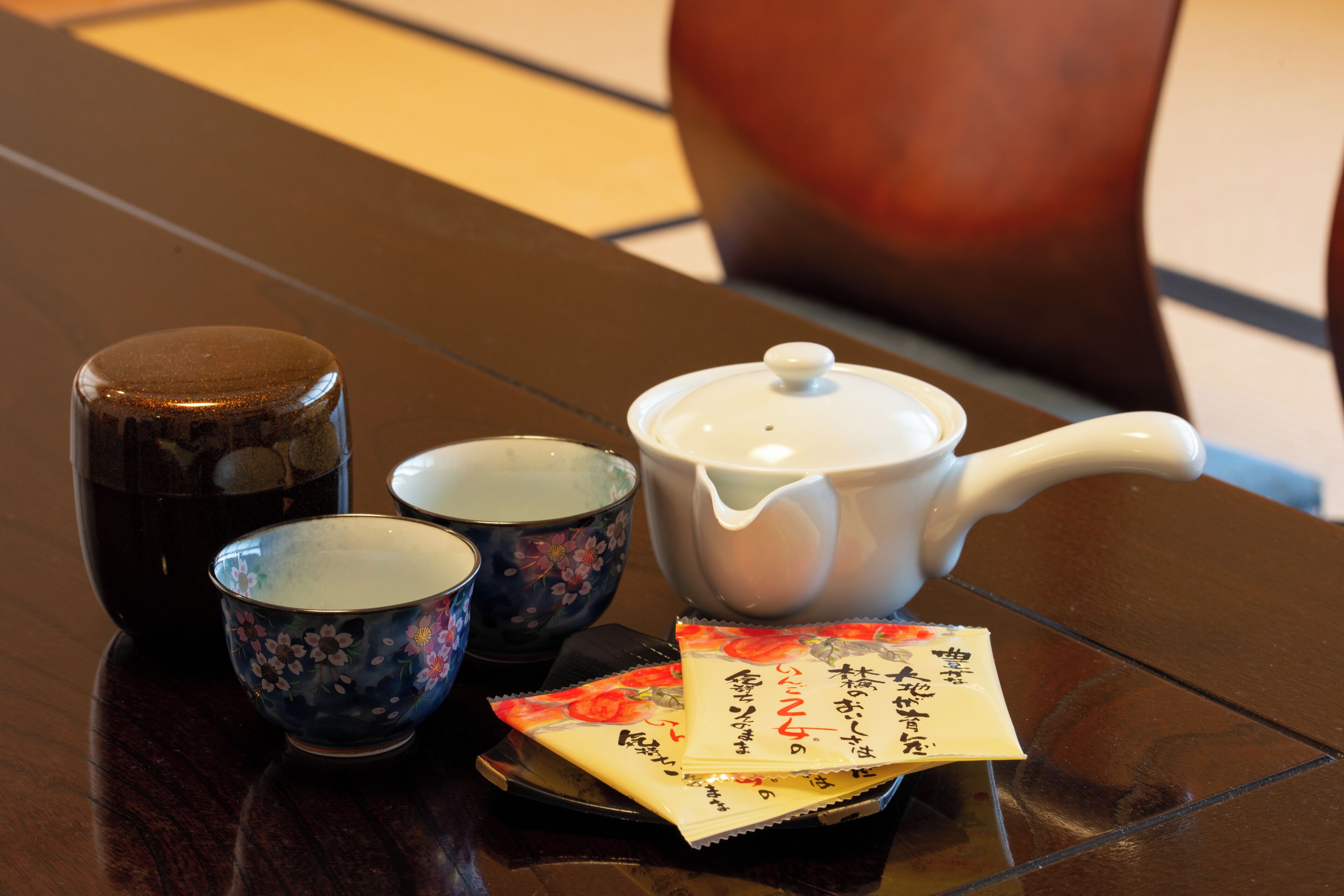 A table with a teapot, two cups, and a packet of tea.