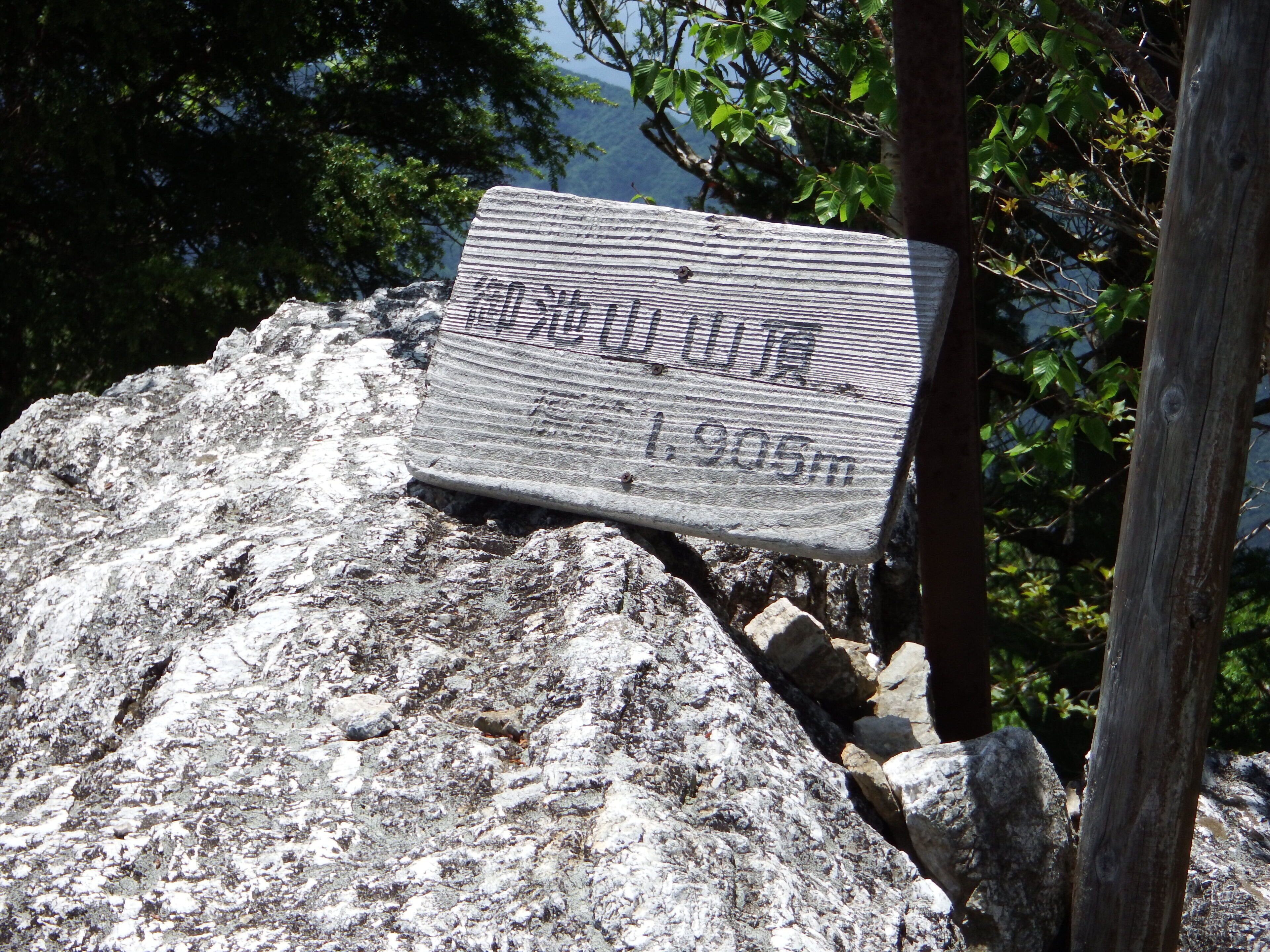 Une vieille pancarte, usée par les intempéries, est fixée à un rocher et indique l’altitude.