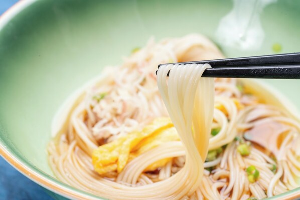 A bowl of noodles with chopsticks lifting a portion. - Shirabiso highlands Amanogawa (Iida)