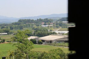 A rural landscape with buildings, greenery, and distant mountains. - Shirokane no Mori (Kikuchi)
