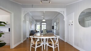 Un espace repas avec une table ronde et des chaises, des murs blancs et un plancher en bois.