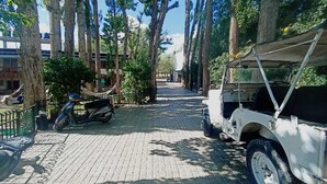 A paved pathway lined with trees, a scooter, and a utility vehicle. - Hotel Shambhala Resort (Leh)