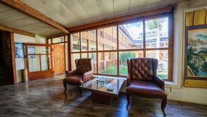 A spacious room with wooden flooring, large windows, and two leather armchairs. - Hotel Shambhala Resort (Leh)