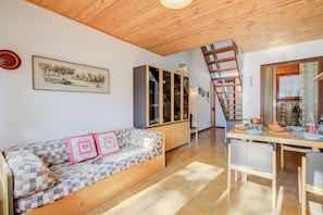 Una sala acogedora con sofá, aparador de madera, mesa de comedor y una escalera.