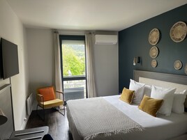 Una habitación de hotel con una cama, una silla, un televisor y una ventana con cortinas.