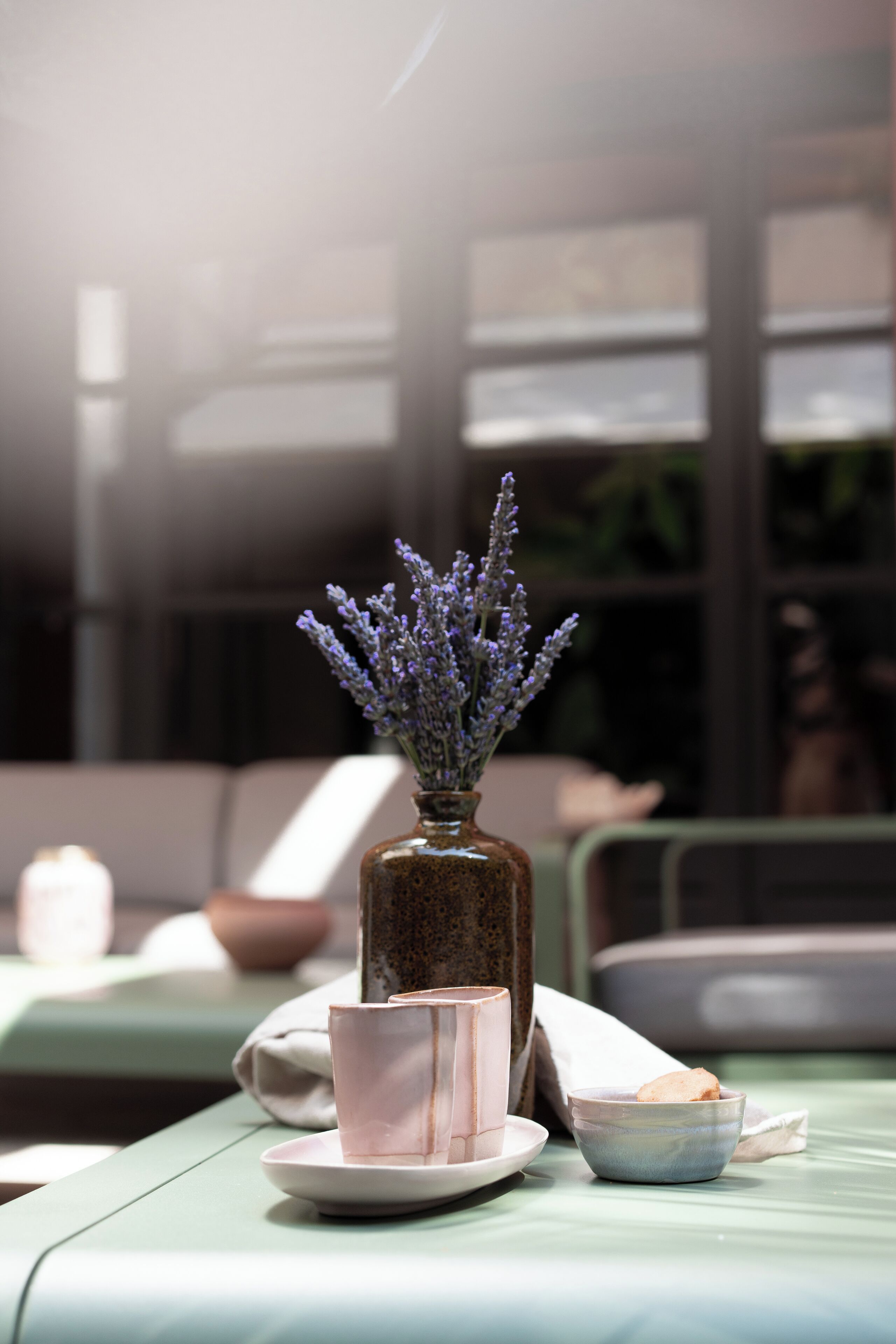 Une table avec un vase de lavande, une tasse et un bol.