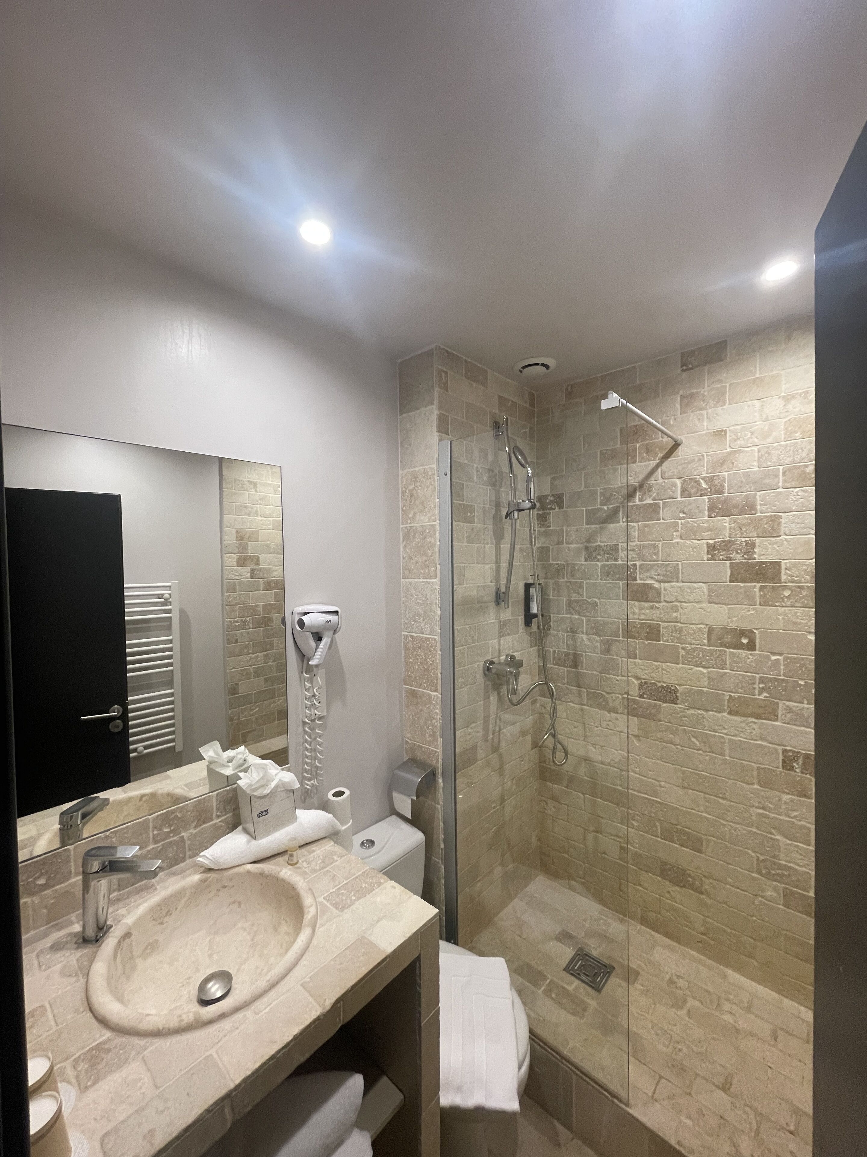 A modern bathroom with a glass-enclosed shower, a beige sink, and a mirror above the vanity.