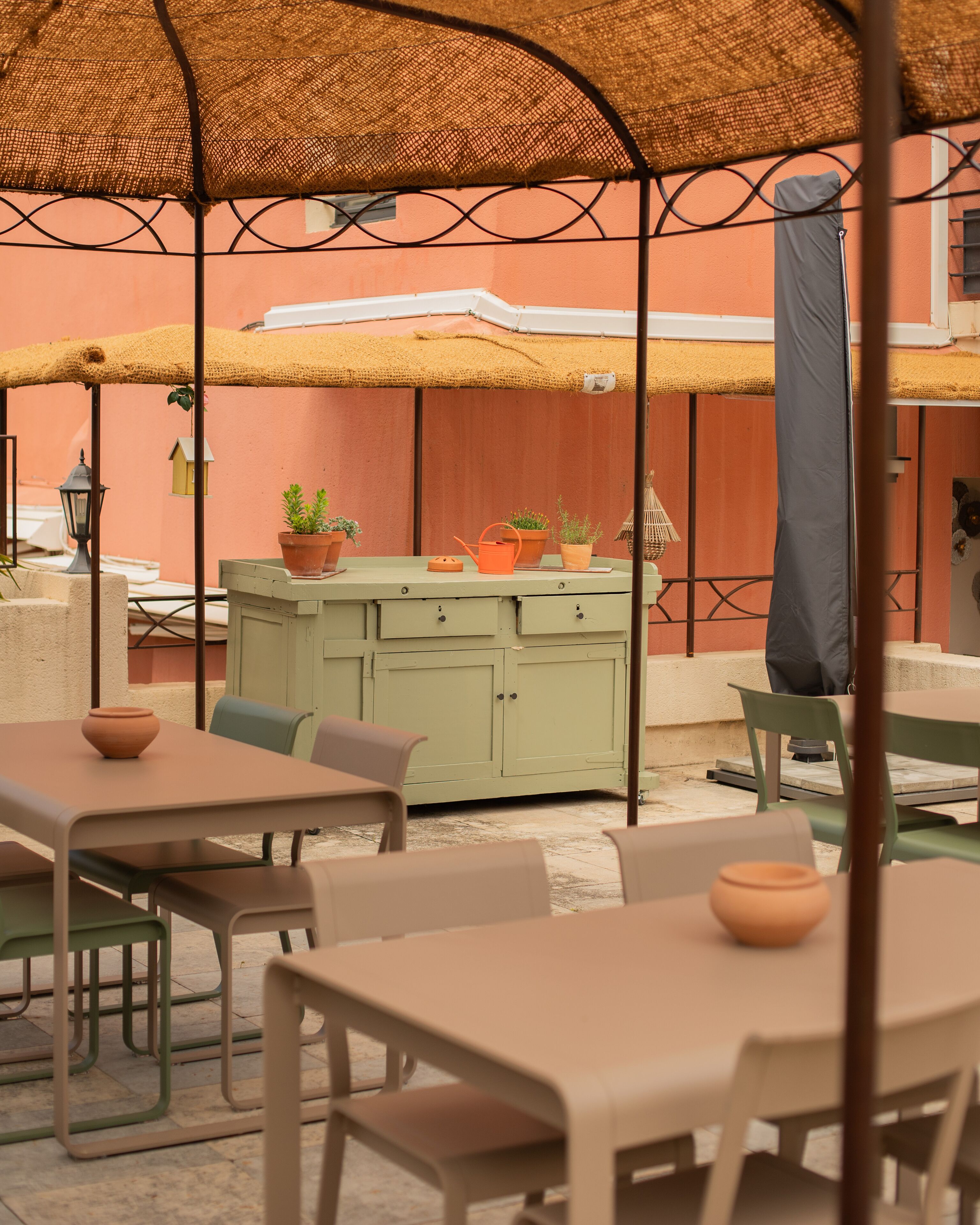 An outdoor seating area with tables and chairs, a green cabinet, and potted plants.