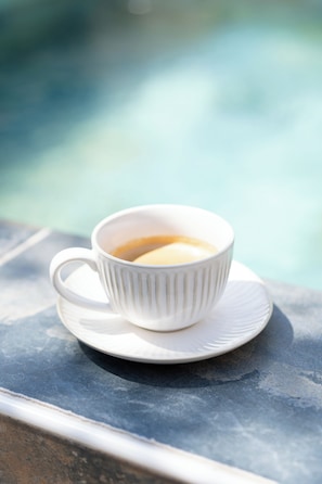 A white cup of coffee on a saucer by a poolside. - Brit Privilège Le Victoria Boutique Hotel (Saint-Paul-Trois-Chateaux)