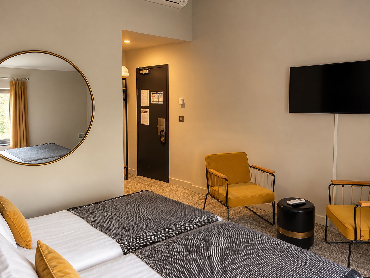 A hotel room with a bed, a chair, a TV, and a door leading to a hallway.