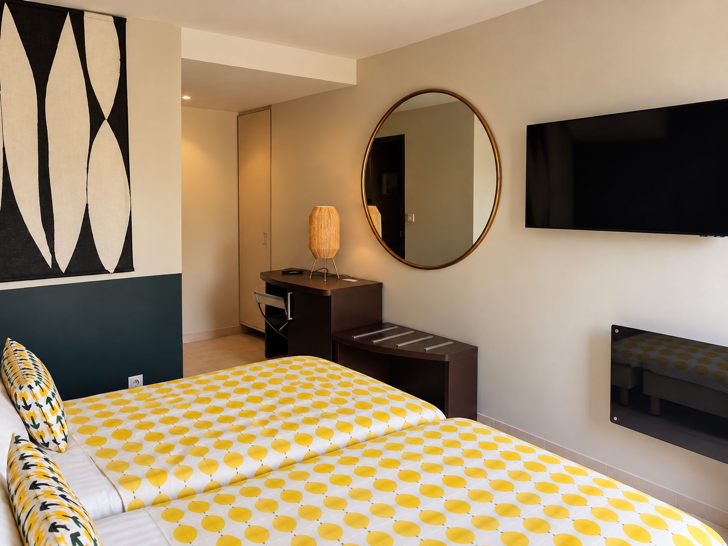 A hotel room with a bed, a desk, a chair, a mirror, and a television.